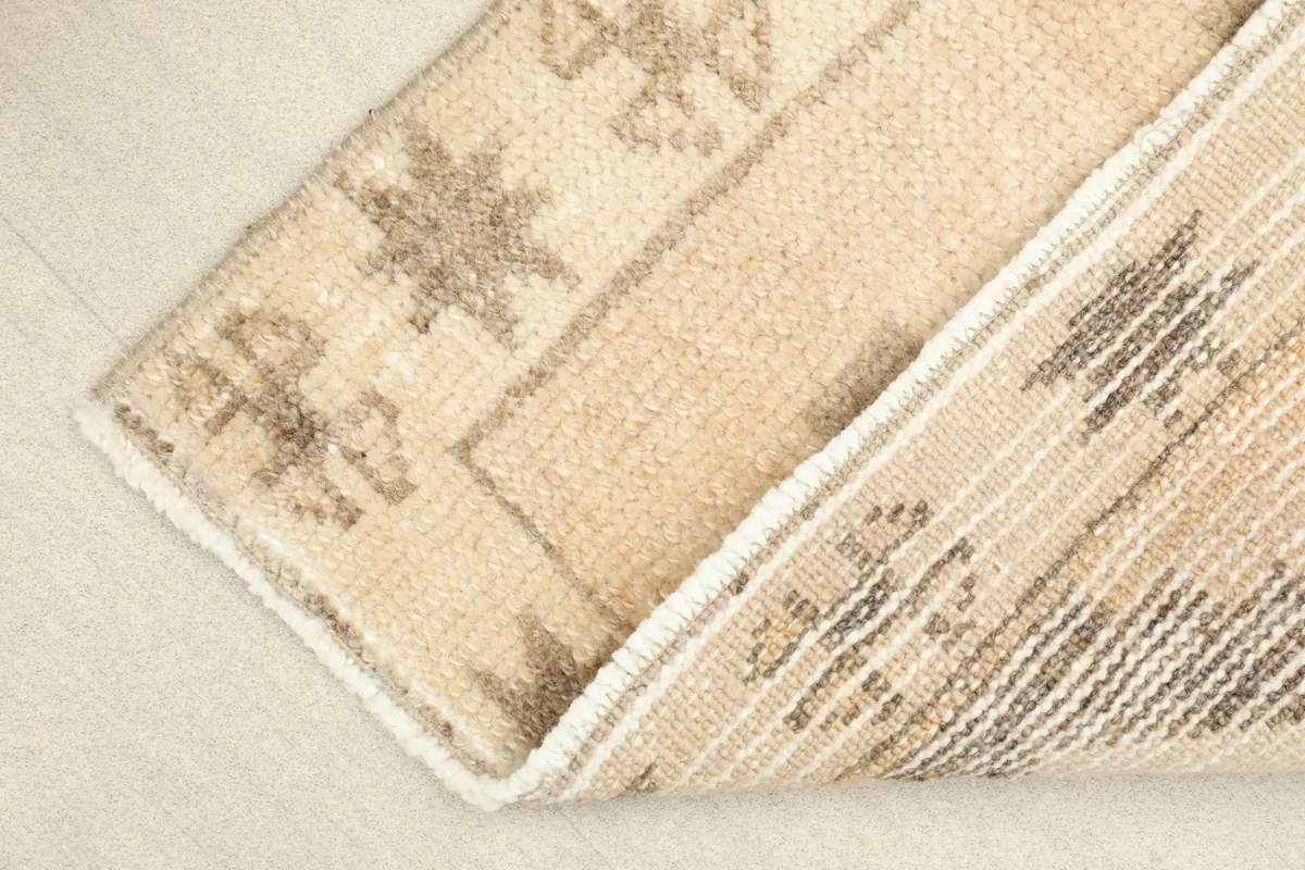 View showing the low wool pile texture and the cotton foundation visible from the underside of the rug.