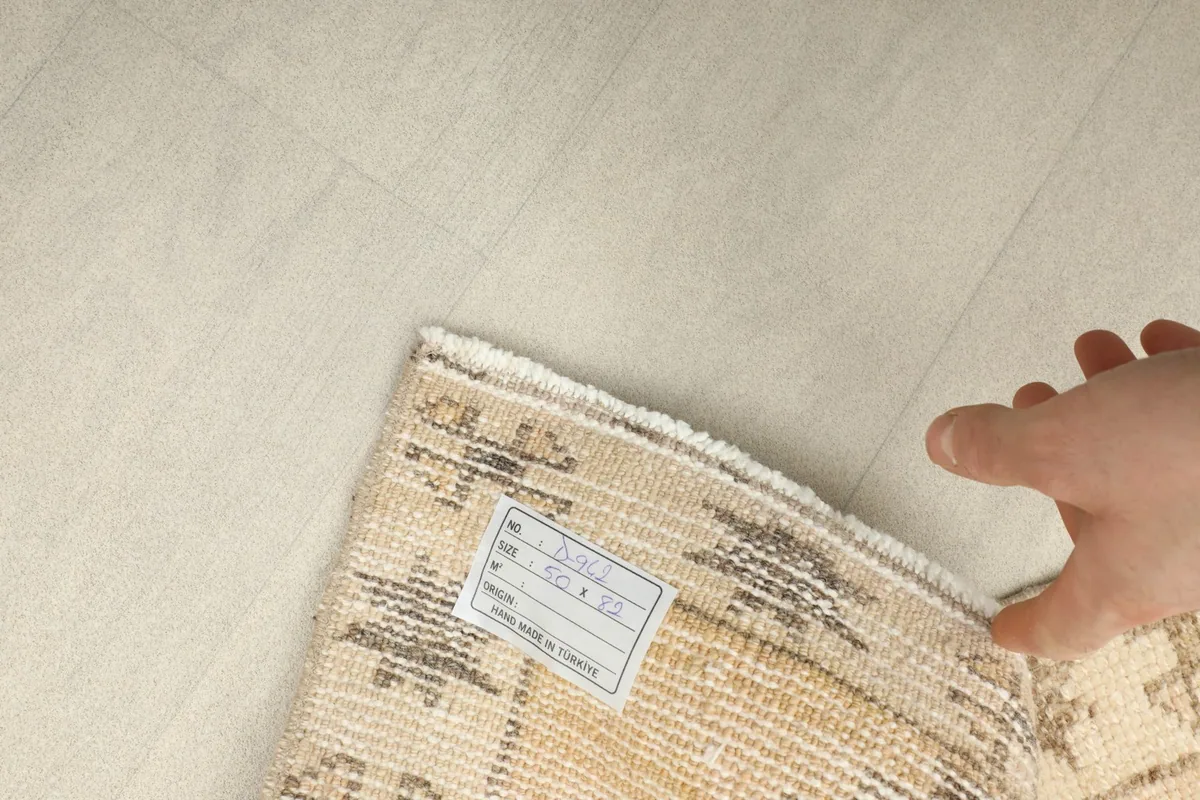 Close-up of the back of the rug with a label, showcasing the hand-knotted weave and cotton foundation.