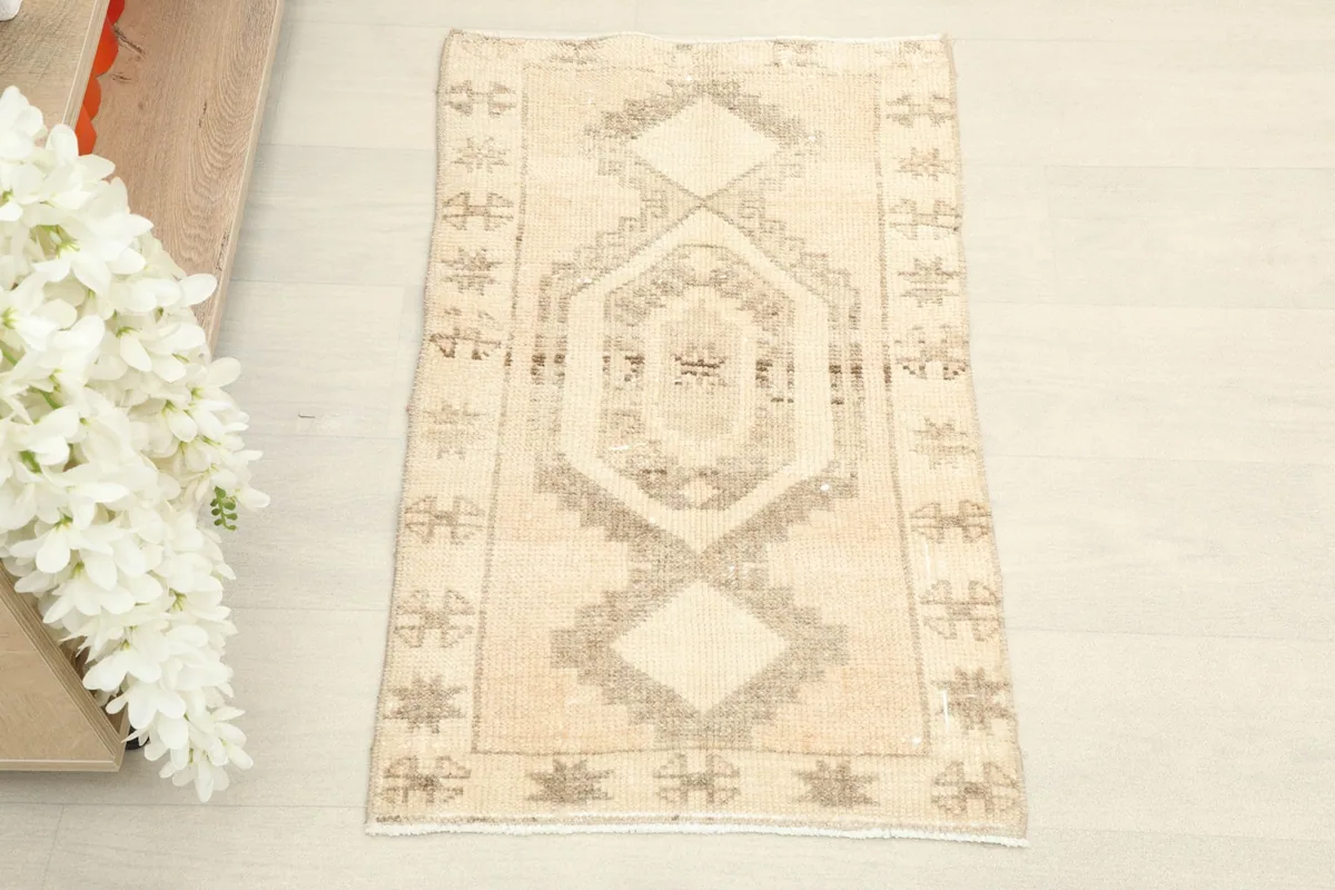 Overhead view of the beige and tan geometric Anatolian doormat rug, highlighting its central medallion.