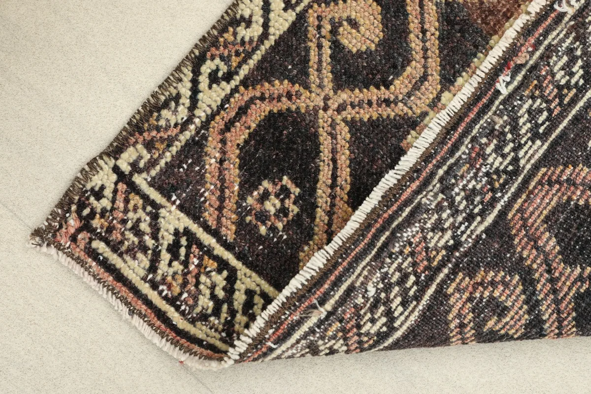 View of the rug folded to show the flexibility and thickness of the vintage wool pile.