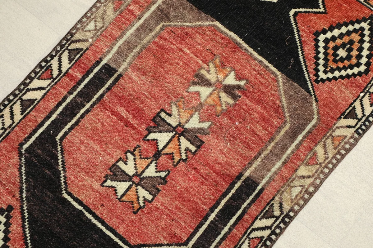 Angled close-up of the rug's central design, highlighting the rust field and black motifs.