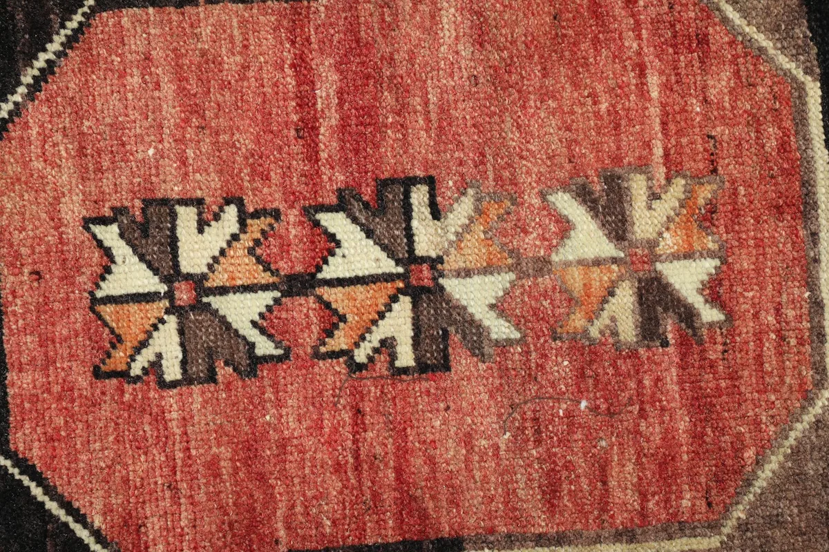 Detailed view of the intricate geometric patterns and color variations within the rug's center.