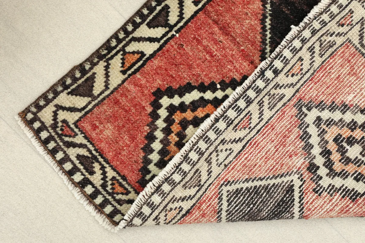 View of the rug folded to show the thickness of the wool pile and the reverse side.