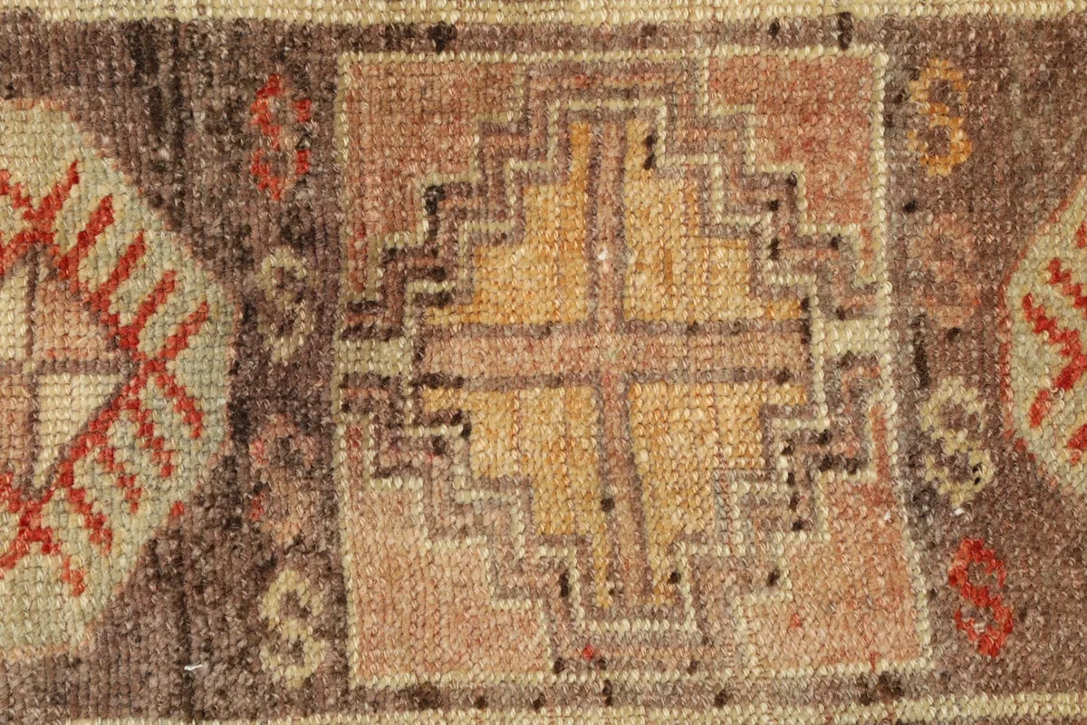 Close-up detail of the central geometric motif, revealing the hand-knotted wool pile and color blend.