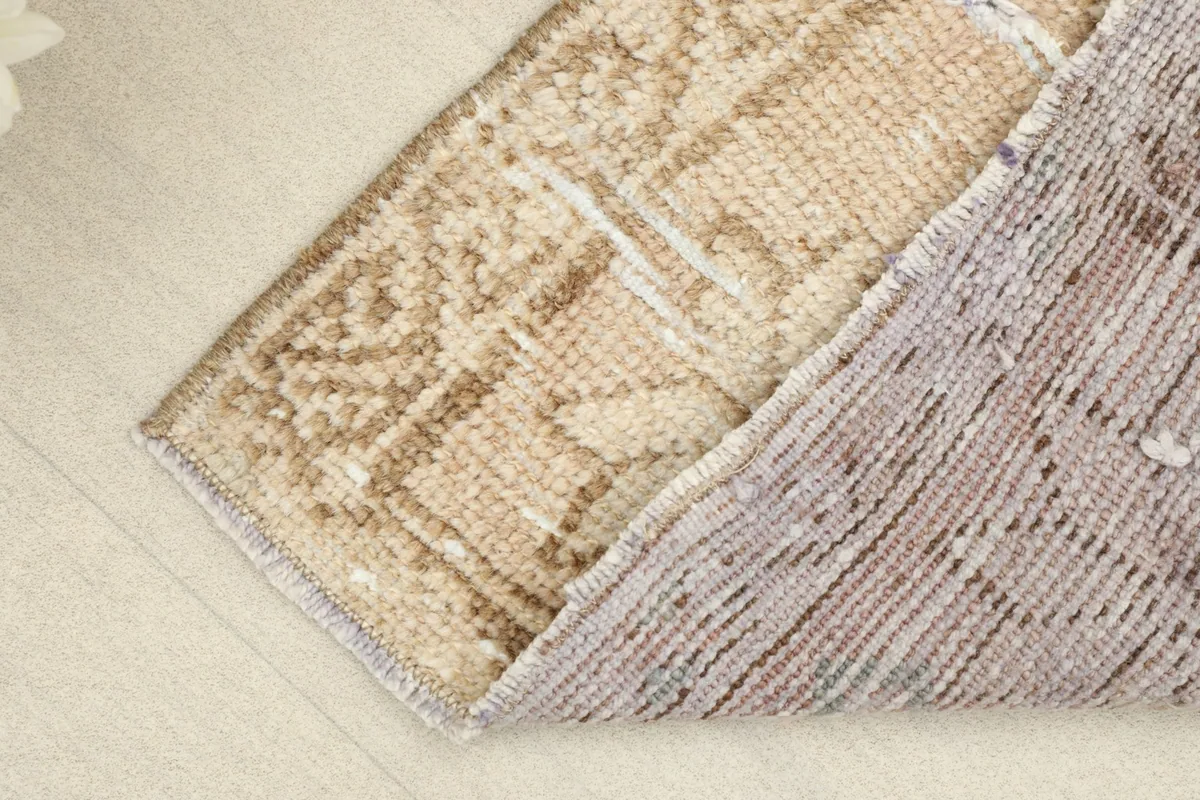 Partial view of the rug's backside, revealing the hand-knotted cotton foundation.