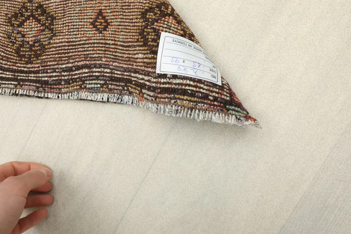 Close-up of the rug's label and fringe, indicating its dimensions and origin