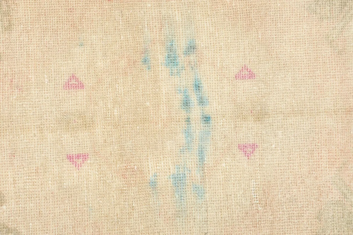 Tight detail of the rug's surface, highlighting the hand-knotted wool and muted colors.