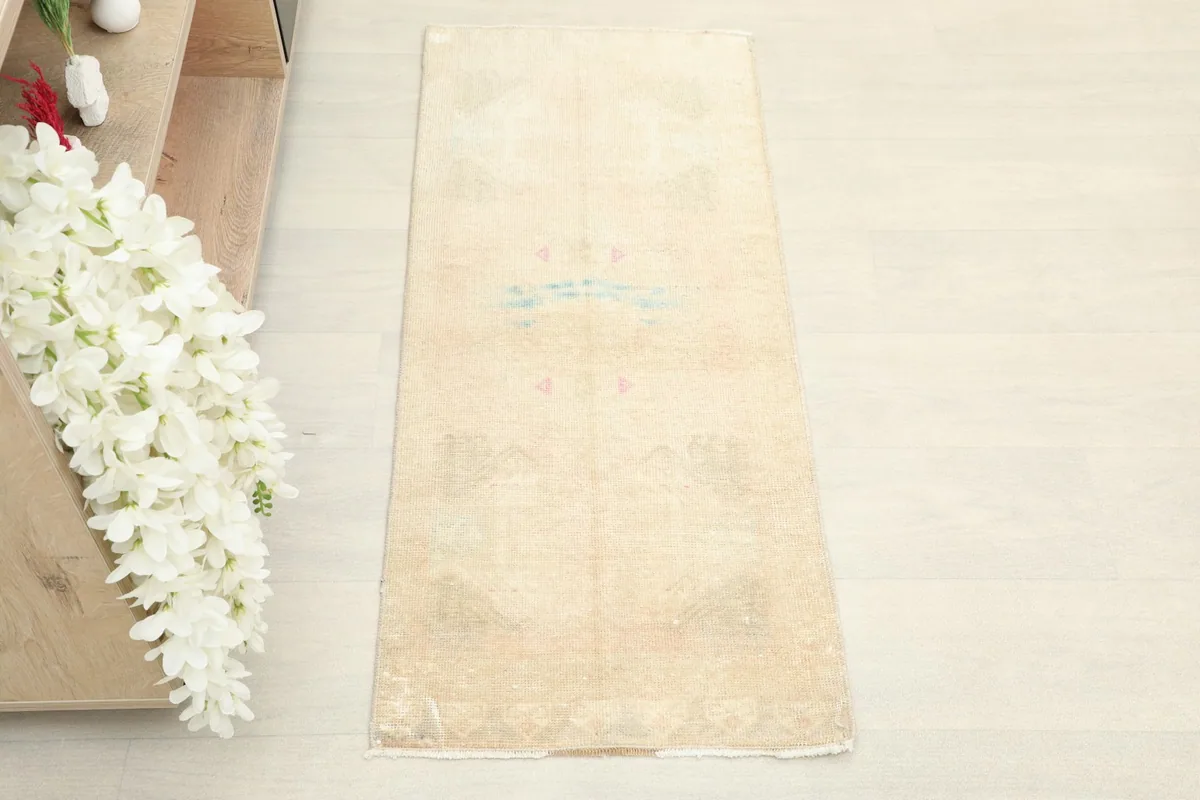Overhead view of the beige rug, showing its full length and subtle pink and blue motifs.