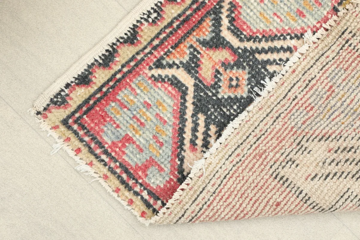 Partial view of the rug's back, revealing the cotton foundation and hand-knotted construction.