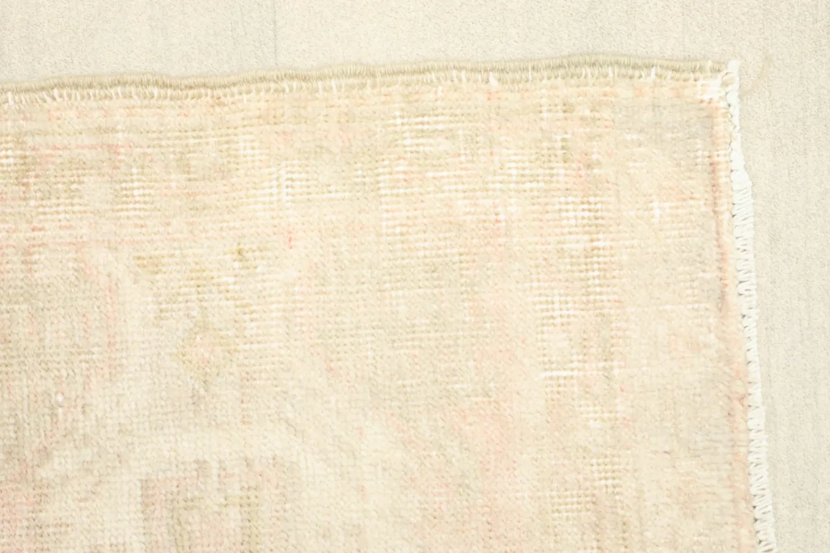 Edge view of the rug's back, showing the woven foundation and subtle backing colors