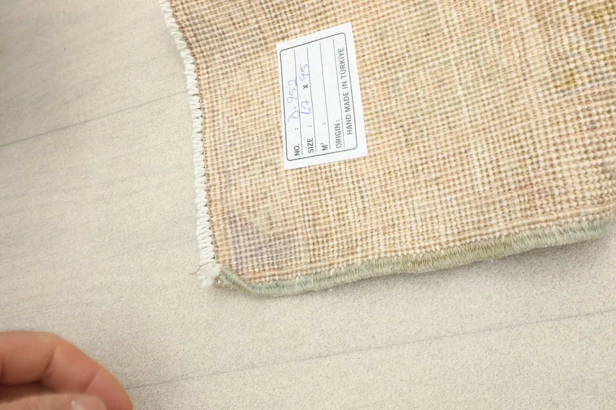 Close-up of the rug's back with a label, showing the hand-knotted structure and material