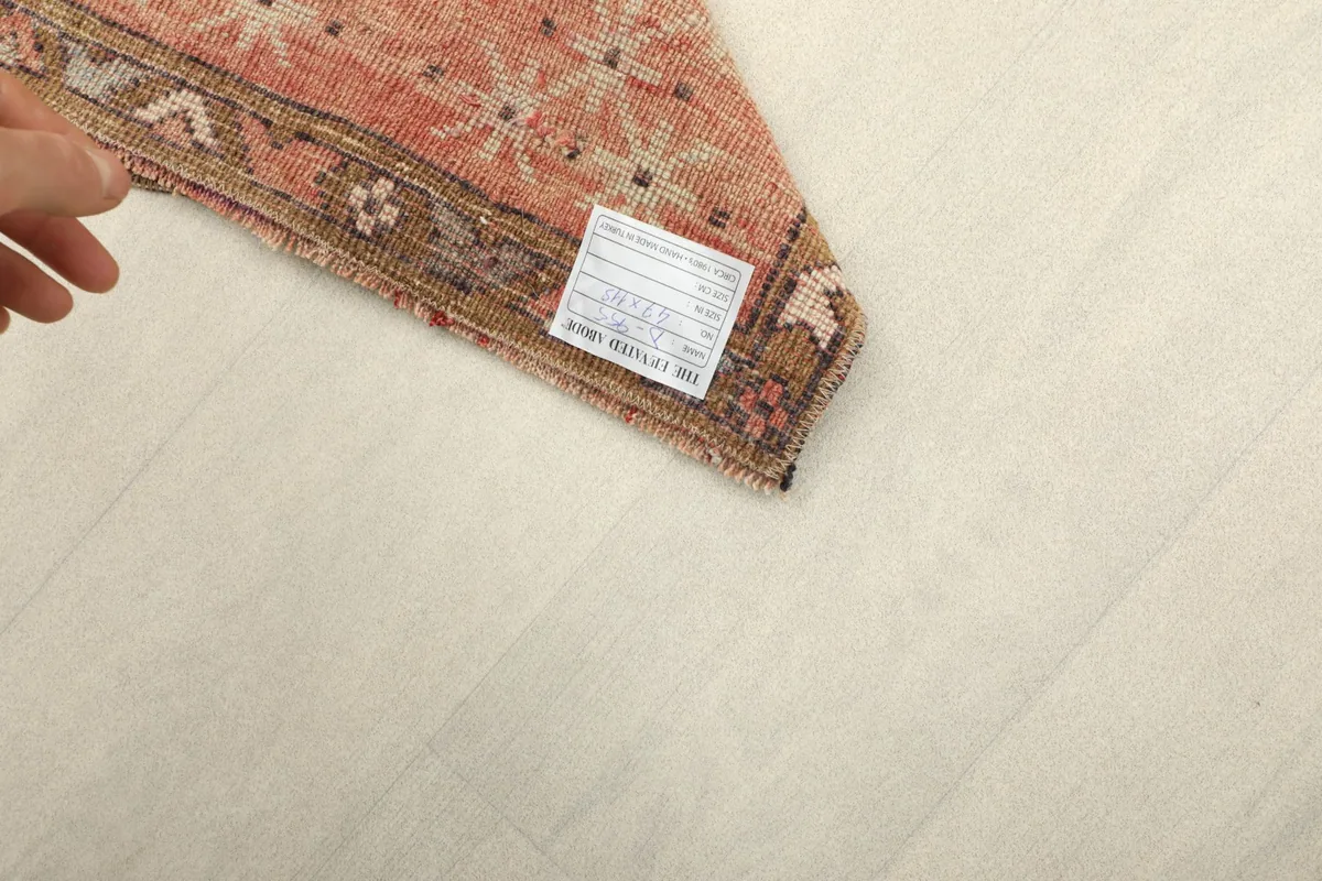 Close-up of the rug's reverse side and a small tag, showing the cotton foundation.