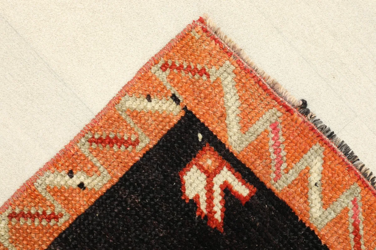 Corner detail showing the orange border with zigzag patterns and a small beige motif.