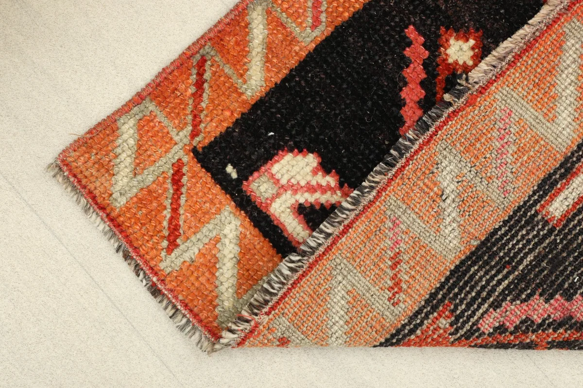 View of the low wool pile and the texture of the orange border, showing signs of vintage wear.