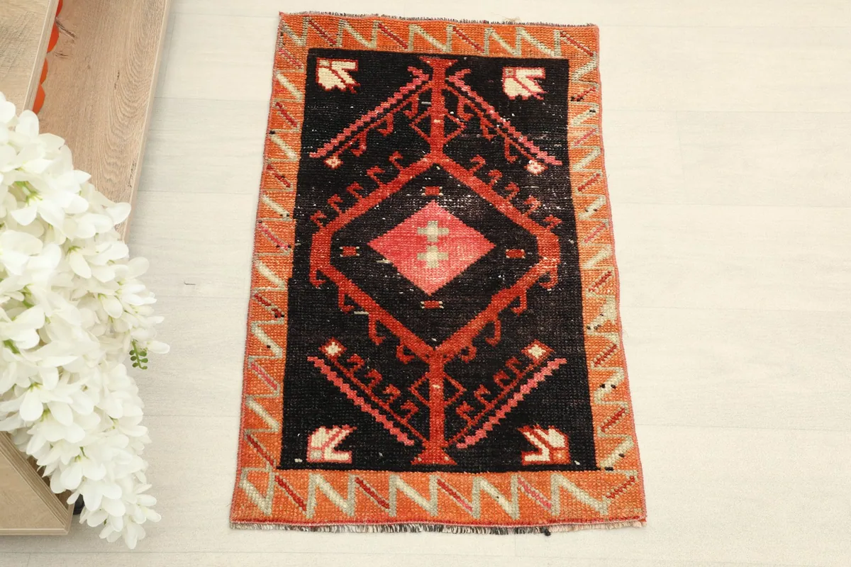 Overhead view showcasing the full black field and orange border of the vintage Anatolian rug.