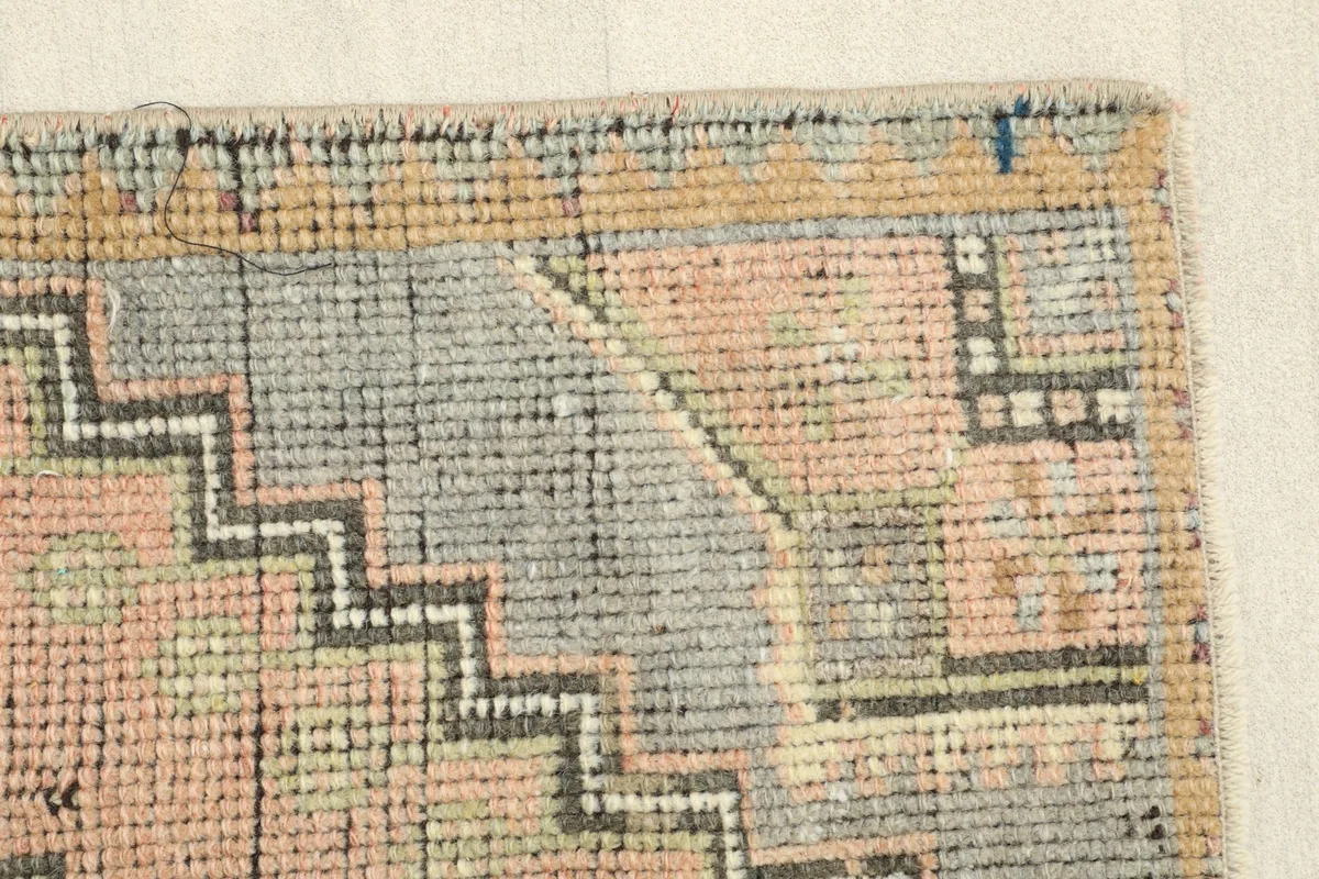 Close-up of a rug corner, revealing the hand-knotted wool pile texture and subtle wear.