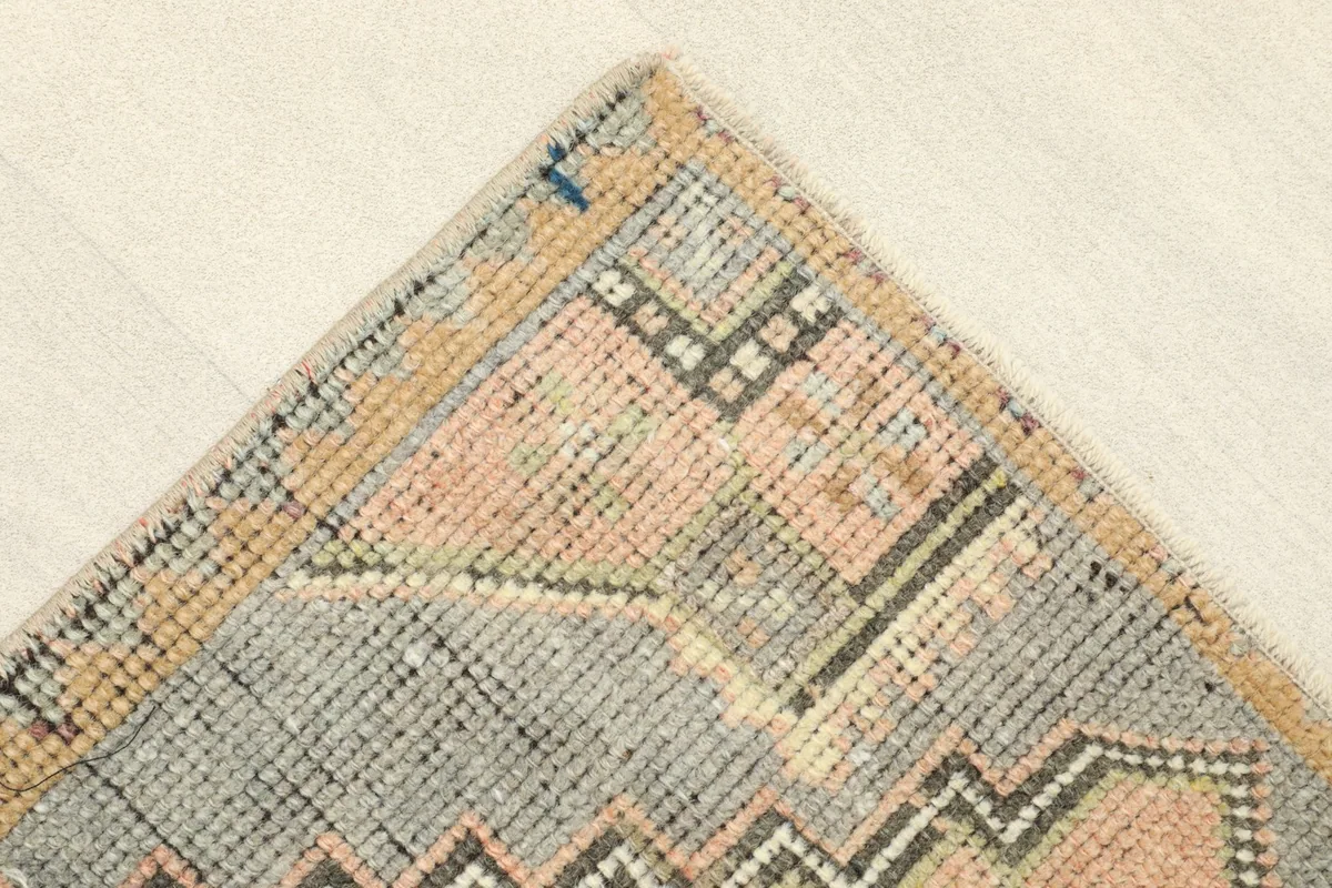 Corner detail showing the gray border, gold accents, and faded rose field of the rug.