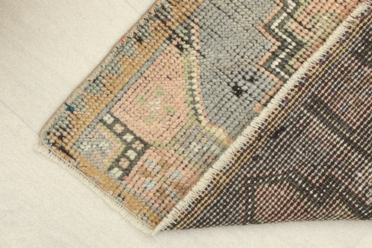 View showing the back of the rug and a corner of the pile, illustrating the cotton foundation.