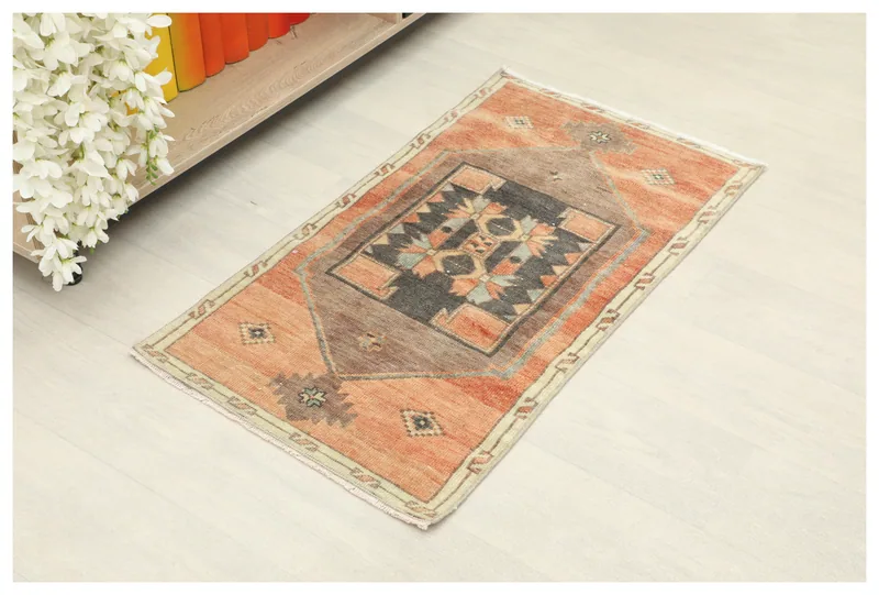 Full top view of the vintage orange and charcoal geometric rug on a white floor
