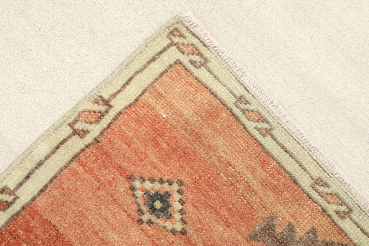 Corner detail showing the orange field, beige border, and small tribal motifs