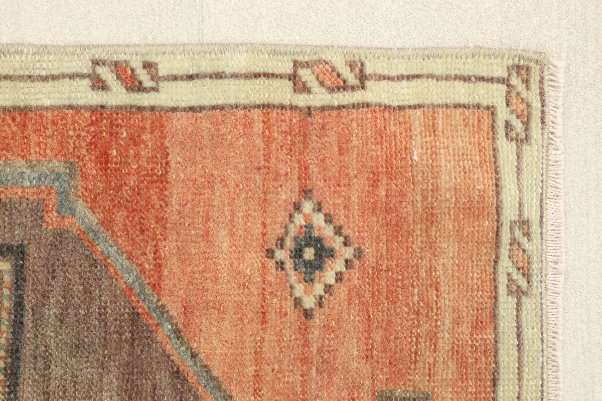 Edge view highlighting the orange field with a small diamond motif and the beige border