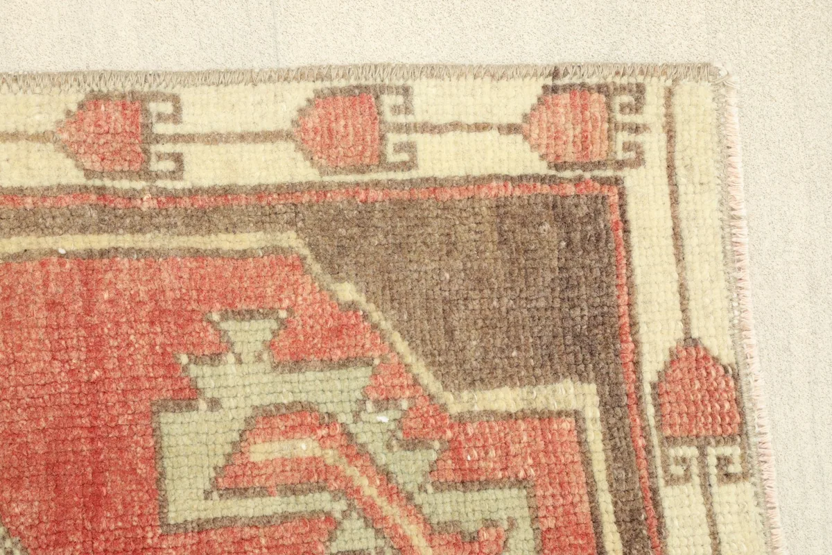 Close-up of the rug's border and a section of the red field with geometric motifs