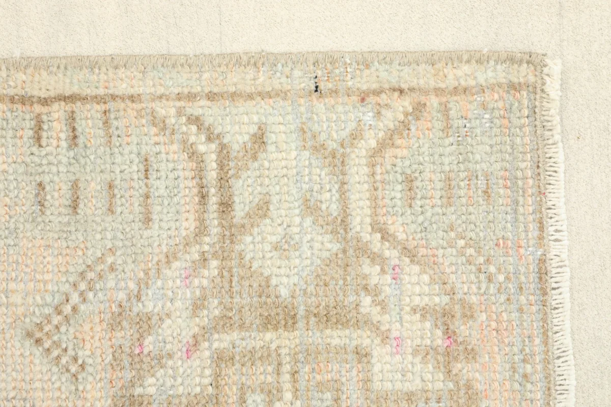 Close view of a section of the rug, showing the faded orange and blue threads within the geometric pattern.