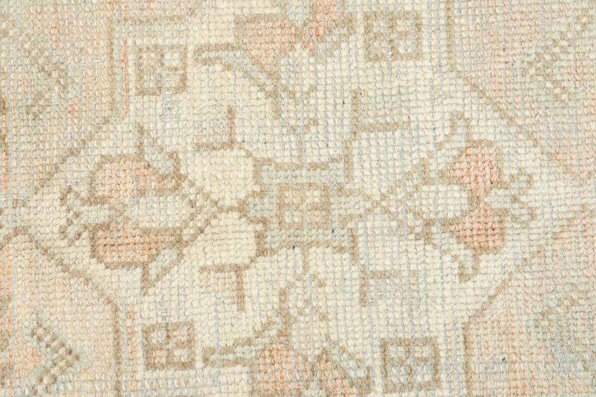 Tight close-up of the low wool pile, showing the texture and faded colors of the rug.