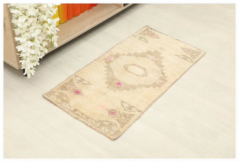 Full overhead view of the beige, brown, and rose geometric vintage Anatolian rug on a white floor.