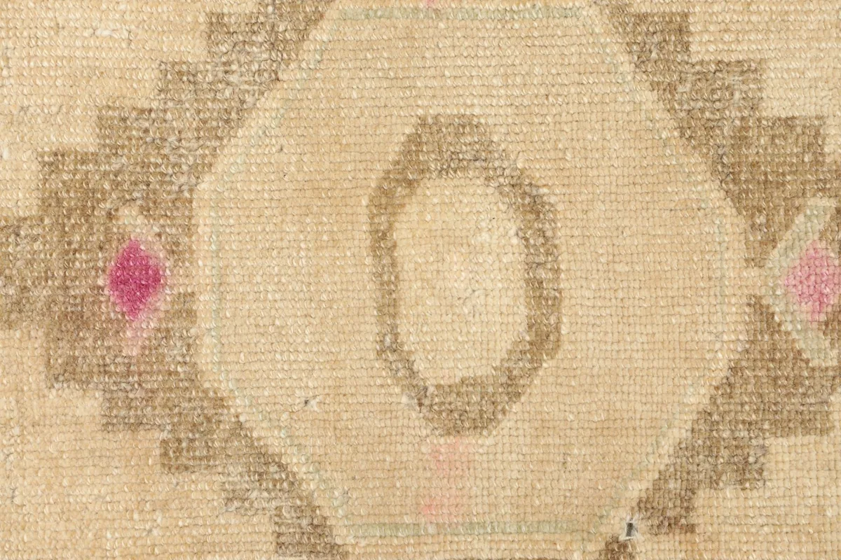 Detailed view of the hand-knotted wool pile and the central motif with its subtle color variations.