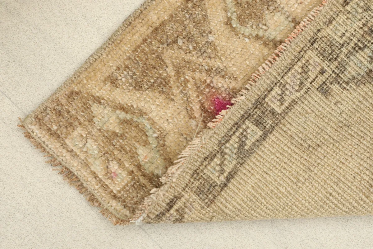 View of the rug folded to show the wool pile texture and the cotton foundation on the reverse side.