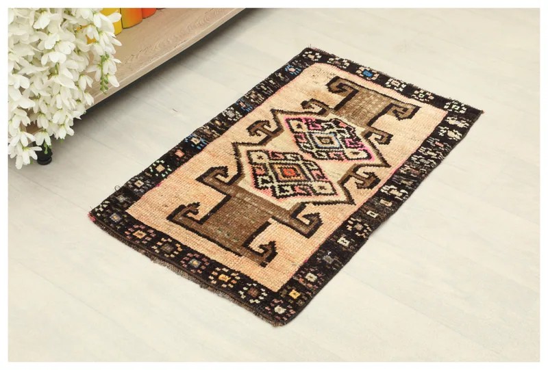 Full top view of the beige and brown tribal geometric rug on a white background.