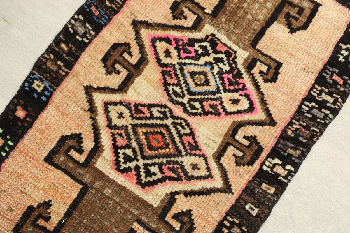 Close-up detail of the central tribal geometric motifs in beige, brown, pink, and blue.