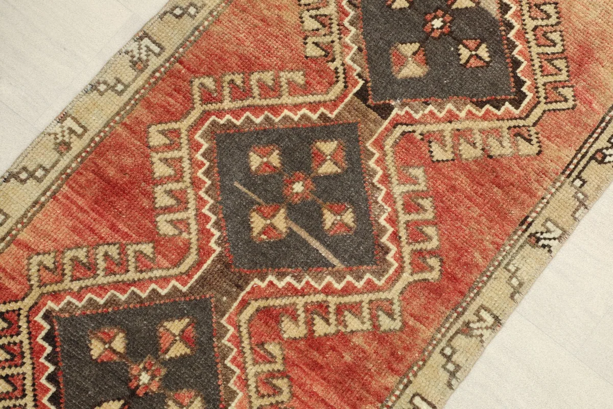 Angled view highlighting the rust field and central charcoal medallions of the vintage rug.
