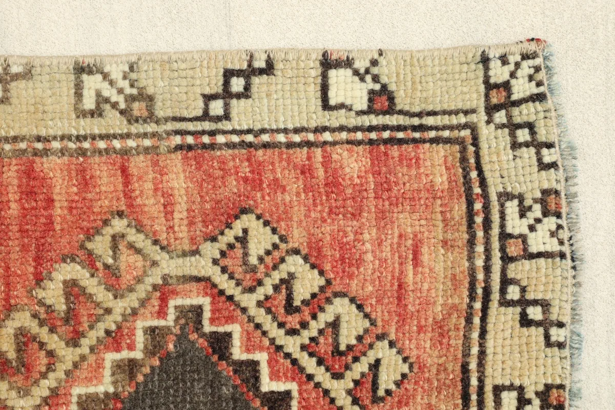Side border detail of the rug, displaying the patterned beige edge and a section of the main design.