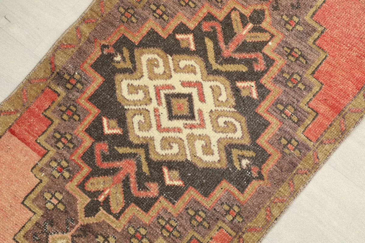 Close-up detail of the central black, brown, and beige geometric motif on the rose rug.