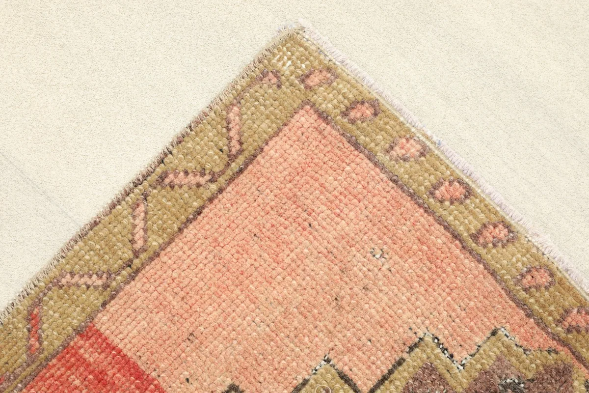 Corner detail showing the tan and rose border design and the texture of the wool pile.