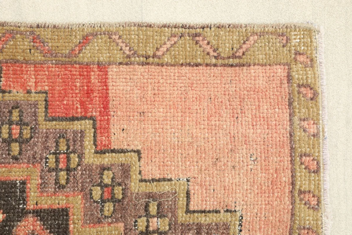 Close-up of the rug's edge, highlighting the subtle border patterns and faded rose field color.
