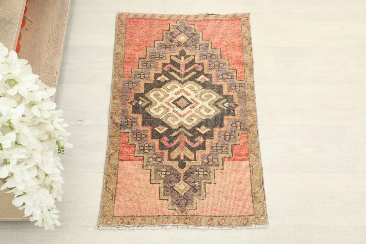 Top-down view of the hand-knotted rose and black Anatolian rug showing its full pattern.