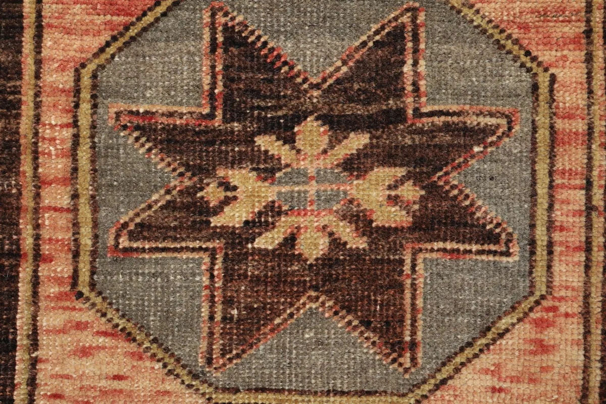 Detailed view of the central brown star motif with subtle yellow elements on a gray background