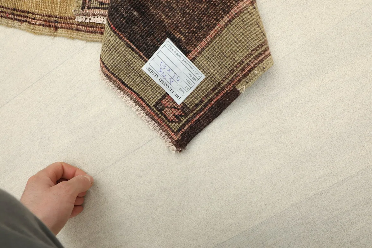 View of the back of the rug with a hand for scale, showing the weave and authenticity tag