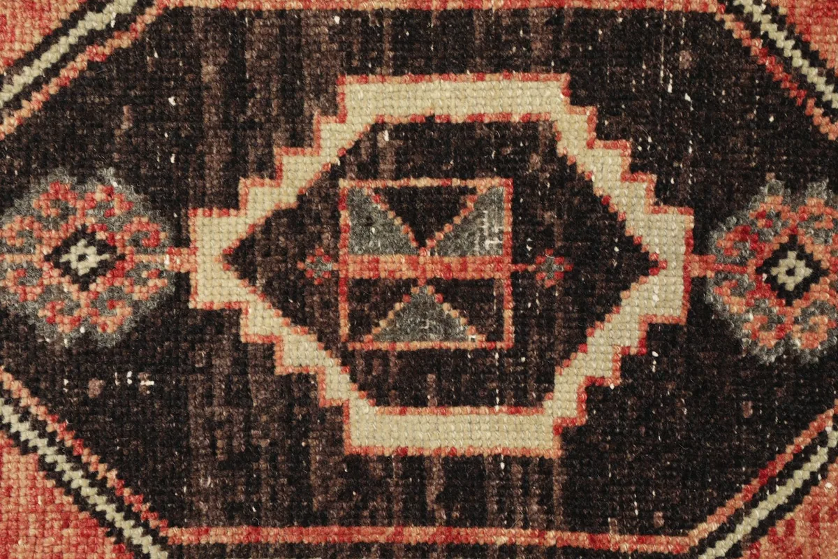 Close-up detail of the black geometric medallion with ivory and gray accents.