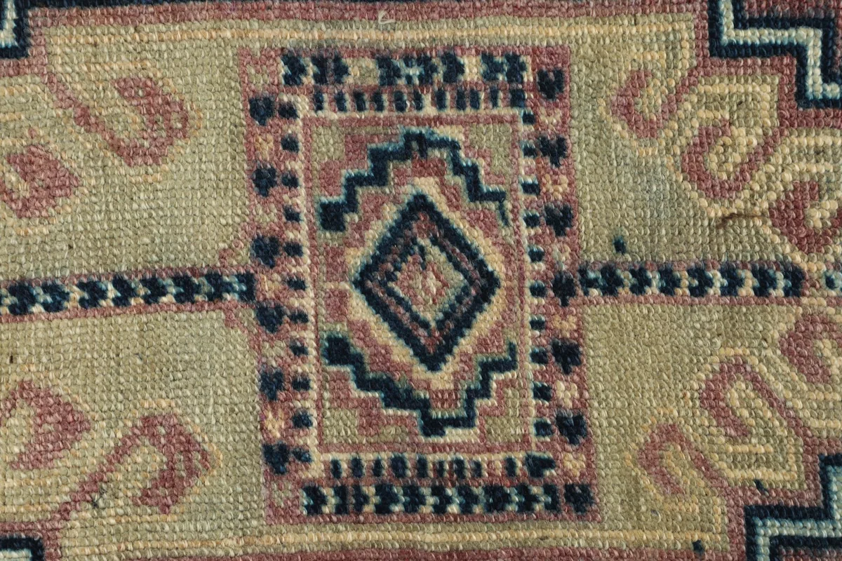Close-up detail of the central tan and navy geometric medallion, showing the wool pile texture.