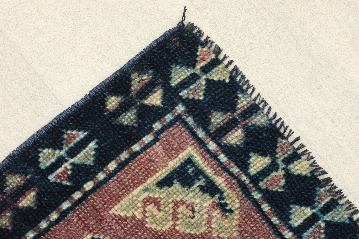 Corner detail of the navy border with its distinct tribal motifs and the transition to the rose field.
