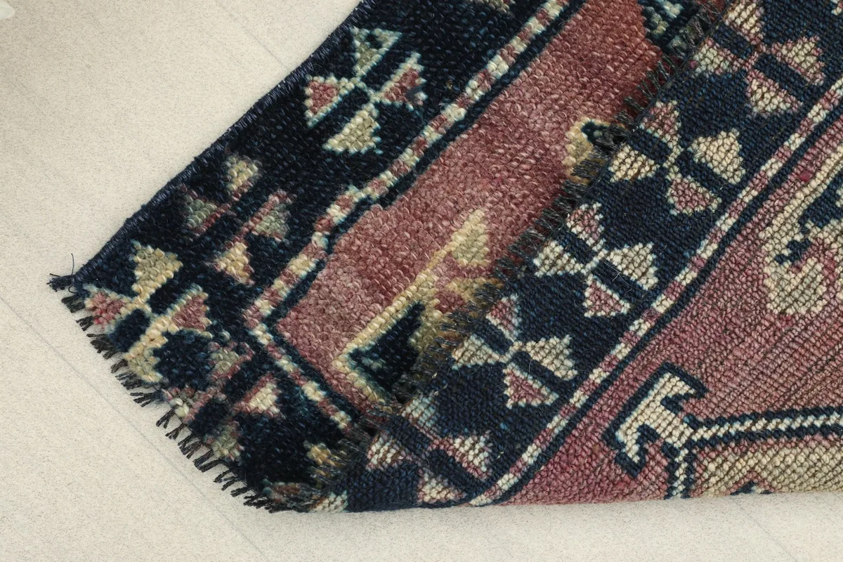 View of the low pile and the texture of the hand-knotted wool, with a slight fold in the rug.