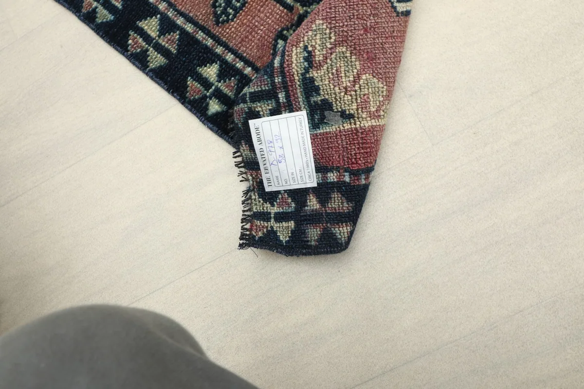 Underside of the rug partially visible, showing the cotton foundation and hand-knotted construction.