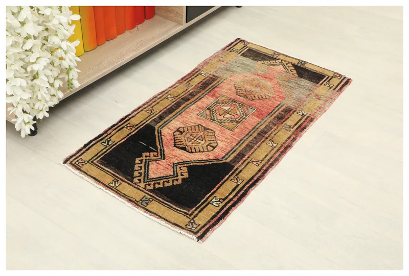 Full top view of the 1'9" x 3'5" rose and black geometric Anatolian doormat on a white background.