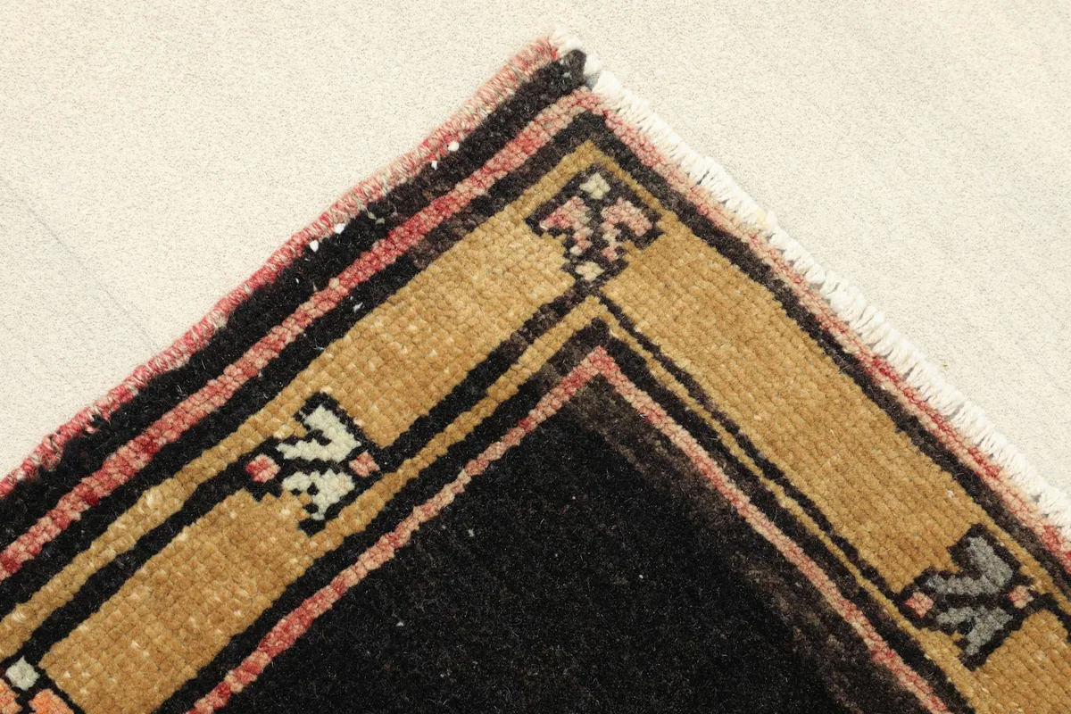 Corner detail showing the black and gold border with subtle rose accents and short fringe.