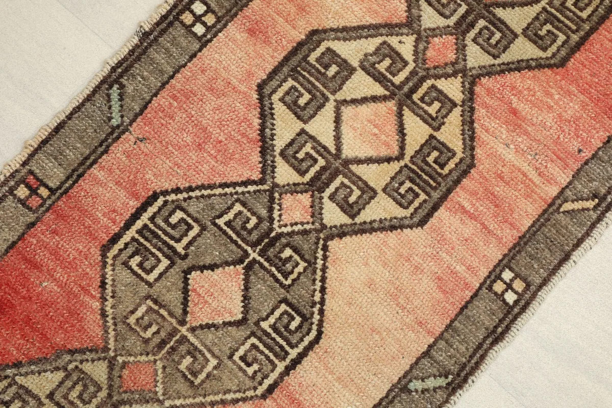 Angled view showcasing the rose and gray colors of the vintage wool rug and its low pile