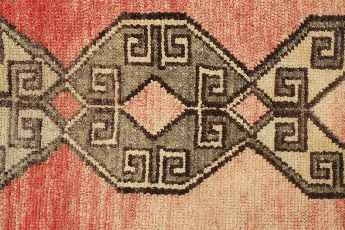 Close-up detail of the intricate gray geometric motifs on the rose field of the doormat